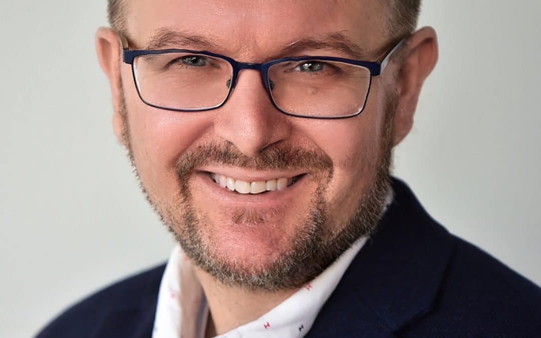 A man in glasses smiling for the camera