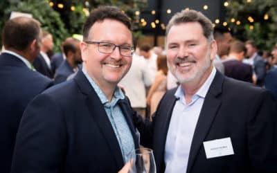 Two men in suits smiling at an event