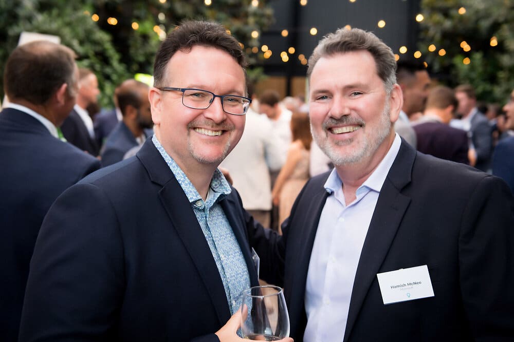 Two men in suits smiling at an event